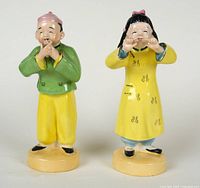 Front view of the porcelain Chinese boy and girl figurines, showing detailed facial features and clothing colors.