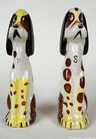 Front view of a pair of tall ceramic dog salt and pepper shakers with letters 'S' and 'P' on their chests