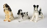 Front view of three ceramic dog figurines showing detailed painting and poses.