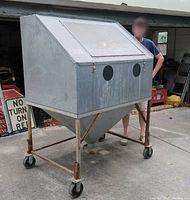 Front and side view of entire sandblasting cabinet on wheeled frame with closed viewing door and arm holes