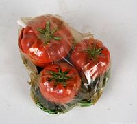 Three red pumpkin-shaped salt and pepper shakers wrapped in cellophane.