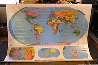 Full view of the open large world map mounted on the wall, showing detailed political divisions in vibrant colors, with oceans in blue background.