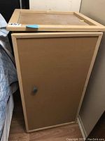 Closed view of one handmade wooden nightstand showing flat top, framed door with knob, and smooth panel