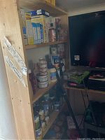 Wooden storage unit loaded with various household products on shelves.