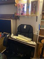 Black ergonomic office chair with items on seat and cardboard shelf pieces behind