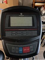 Close-up of the elliptical machine's control console with digital display and buttons for program selection, start/stop, and navigation.