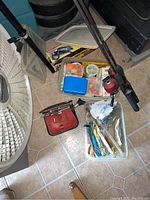 Overview of fishing equipment including rods, boxes of lures, bobbers, mini screwdriver set, foot air pump.
