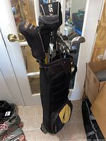 Full view of golf bag holding multiple golf clubs with head covers and some clubs visible