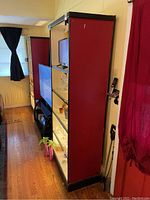 Side view showing the red fabric sides, black frame edges, and glass shelves with back panel.
