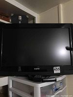 Front view of 32 inch Sanyo TV showing black frame, screen, and logo. Remote control visible.