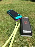 Two step platforms and two green exercise poles placed on the grass.