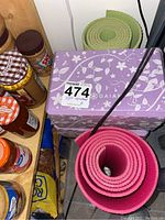 Pink and green rolled foam yoga mats with Gaia box containing foam blocks, placed near pantry items.