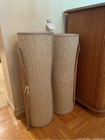 Photo of two rolled beige area rug runners standing upright.