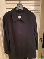 Front view of the women's black wool coat with button closure.