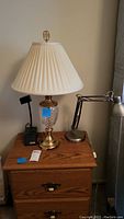 Wide shot showing the crystal lamp with pleated shade on a wooden nightstand, flanked by two desk lamps