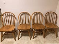 Four oak dining chairs arranged in a row showing overall condition and style.