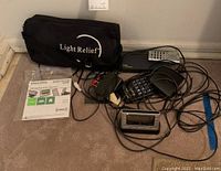 Full view of the lot showing Delphi CM satellite radio receiver, Light Relief bag, cables, remote, and Royal dictionary.