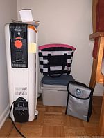 Full lot showing DeLonghi heater on wheels, cooler underneath black and white tote bag with pink accents, and gray insulated tote bag in the foreground.