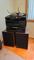 Stacked stereo components including JVC DVD player on top, TEAC CD/cassette player in middle and Pioneer receiver on bottom, with two speakers in front.