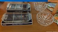 Mikasa Satin Rose relish trays in original boxes with clear segmented glass and floral handles, two crystal bowls with star cut patterns, coasters and Tupperware seen reflected in mirror nearby.