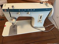 Side view of Singer Fashion Mate 257 C sewing machine showing white and blue body with knobs and electric cord.