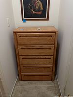 Full front view of the tall oak wood dresser showing all five drawers and overall shape.