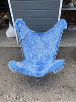 Blue fuzzy butterfly chair placed outdoors showing full view of fabric and frame.
