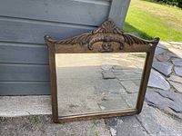 Full view of the antique wooden framed mirror showing rectangular shape and ornate carved top detail.