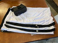 Projection screen folded with black edges, showing metal grommets, lying on a surface with a VR headset placed alongside.