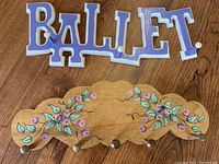 Top view of wooden folk art shelf with floral painted design and two brass hooks on front