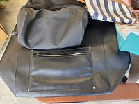 Photo of six purses on a surface showing the gray, black, woven straw, striped canvas, teal, and maroon purses.