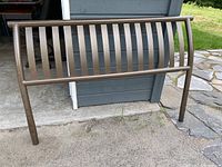 Full view of the queen metal headboard showing the curved vertical slat design and bronze finish.