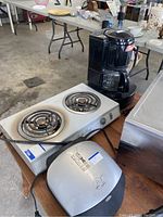 Photo showing coffee maker, electric stove, George Foreman grill, and stainless steel appliance.
