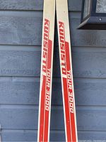 Close-up photo of Kuusisto Tour 3000 cross country skis showing the red and cream coloring and branding.