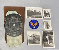 Overview photo showing the Aerial Dead Reckoning Computer alongside a leather case, one patch, and six black and white photographs.