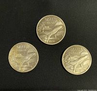 Three round 2012 Maui trade coins showing front whale design with floral elements and date.