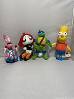 Four small plush toys lined up: Energizer Bunny, Ruby Gloom, Leonardo TMNT, Bart Simpson