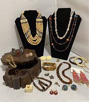 Full view of lot showing necklaces on black displays, bracelets, earrings, and small cream-colored box with ring and wooden box storage.