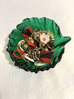 Glass bowl filled with assorted jewelry pieces from above showing variety and colors.