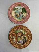 Photo of two limited-edition Heinrich porcelain plates featuring French fairy tale scenes with decorative gold and colored borders, showing wear.