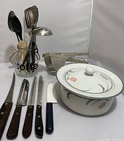 Wide view of lot showing knives, Dansk casserole, utensils in jar, roasting rack