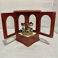 Front view of wood and glass music box with doors open showing carousel inside