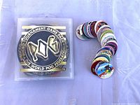 Closed micro tournament game pack case next to a stack of various extra pogs showing colorful designs.