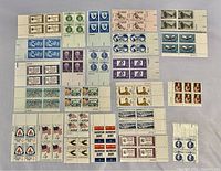 Top side view of 24 blocks of unused U.S. stamps arranged in grid with various designs and colors.