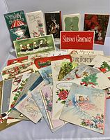 Over 30 vintage greeting cards spread out showing diverse holiday and celebratory designs, some standing and some laid flat.