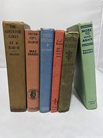 Front view of the six books standing in a row showing titles and condition of spines and covers.