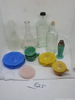 Full lot of Akro Agate Ware colored glass plates, covered dish, small cups and old bottles on white background