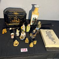 Wide shot of lot showing black lacquered box, porcelain vase, painted scroll case, various figurines, decorative pipe, and small cup.