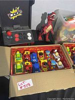 Photo showing the ICade game controller, dinosaur figurine, and box of assorted toy cars