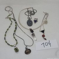 Full lot showing multiple sterling silver necklaces with various gemstone pendants including green stones, snowflake obsidian, crystal and amethyst, black and red stones.
